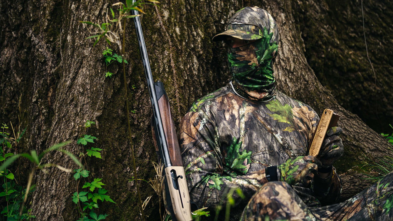 Hunter calling turkey in camo next to tree