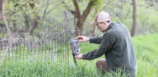 setting up a trail cam on a fence